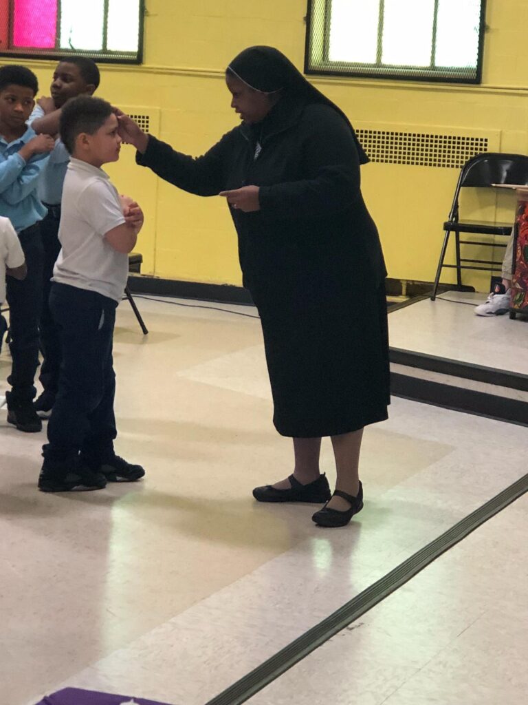 Sr. LaKesha Church, CPPS, distributes ashes to her students.